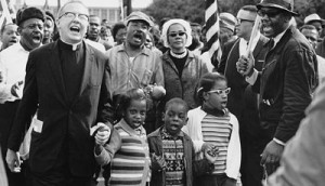 Dr. Martin Luther King, Jr., was a champion for equity in education. Civil Rights Movement co-founder Dr. Ralph David Abernathy and his wife Mrs. Juanita Abernathy (not pictured) follow with Dr. and Mrs. Martin Luther King, Jr., as the Abernathy children march on the front line, leading the Selma to Montgomery March in 1965. The children are (left-right): Donzaleigh Abernathy in striped sweater, Ralph David Abernathy III, and Juandalynn R. Abernathy in glasses. Name of the White Minister in the photo is unknown.                (Abernathy Family Photos/Wikipedia Commons)