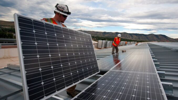 Workers install photovoltaic solar panels on the roof of the National Renewable Energy Laboratory's Research Support Facility in Golden, Colo. in 2013. (Source: U.S. Department of Energy)